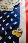 Bitcoin physical coins on American flag background with dollars