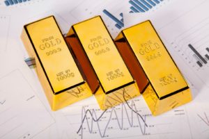 Three gold bars sitting atop financial documents