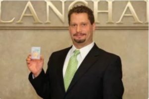 David Zanca, Senior Portfolio Manager, holding slabbed coin with Blanchard signage in background