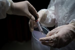 Healthcare workers placing specimen tube in plastic bag