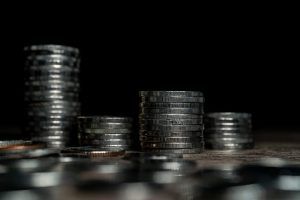 Stacks of silver coins with black background on mirrored surface