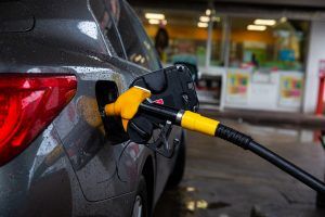 Car filling with gas at pump. In front of gas station