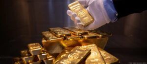Professional handling of gold bars with white cotton gloves showing proper precious metals handling methods.