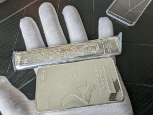 Gloved hands holding silver bars safely to avoid surface damage.