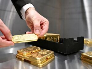 Close-up-of-a-gold-bar-being-handled-next-to-a-black-gold-storage-tray-used-for-organizing-bullion-bars-during-inspection-or-counting